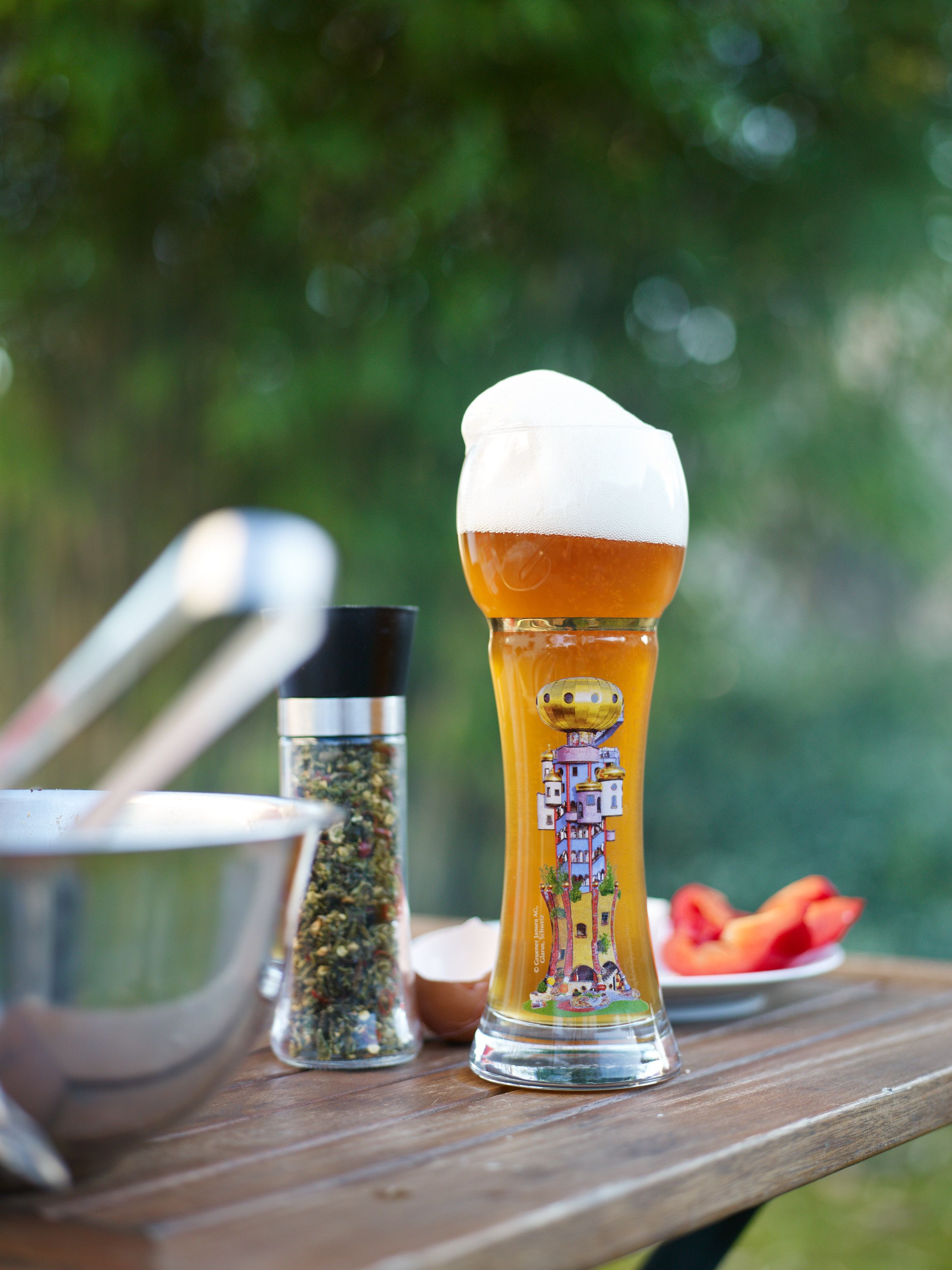 A pint of German wheat beer, or: eine halbe Weiße; the glass displays the brewery's tower, designed by Friedensreich Hundertwasser