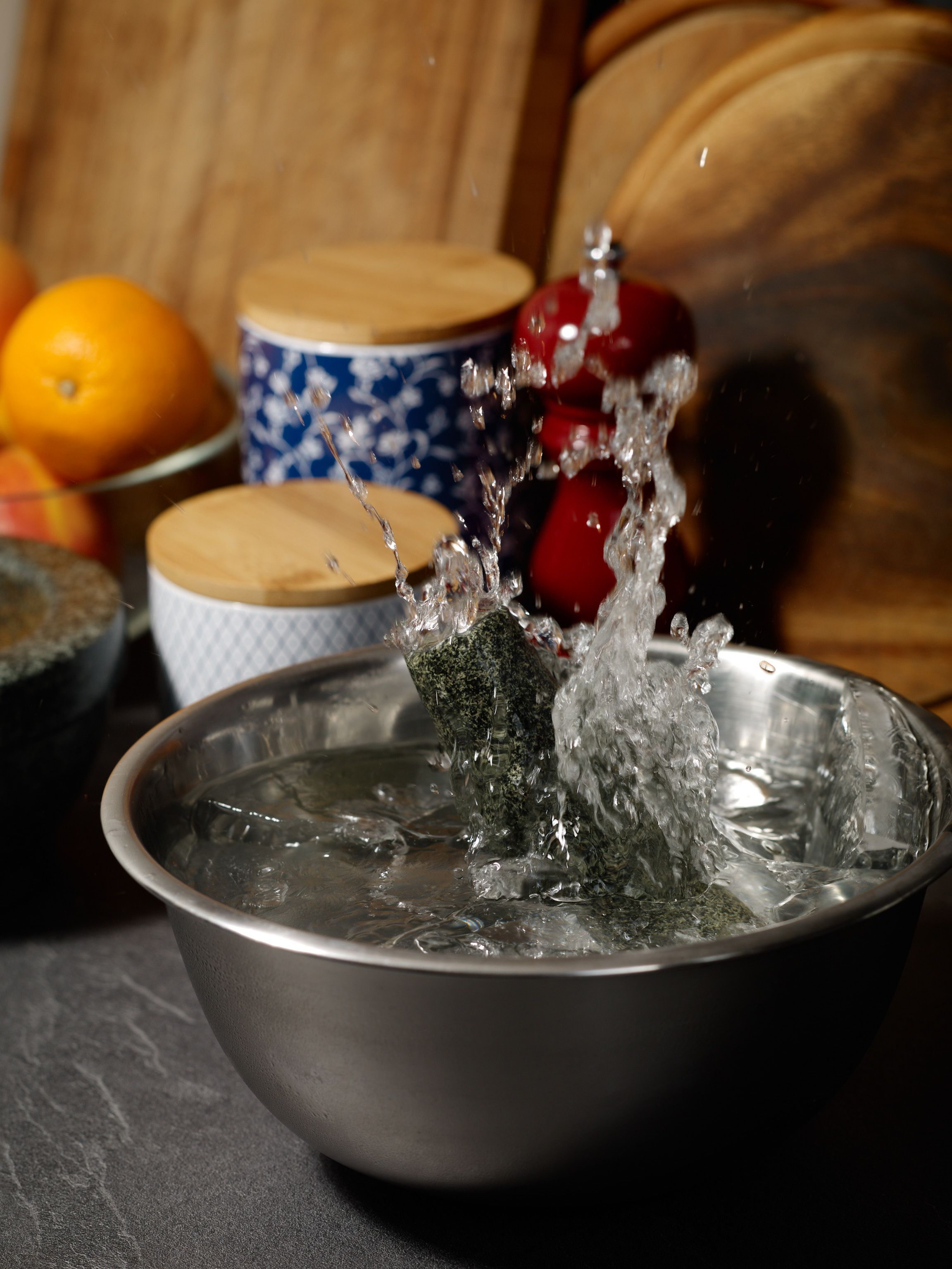 The crust on a bowl of ice water is being smashed by a granite pestle