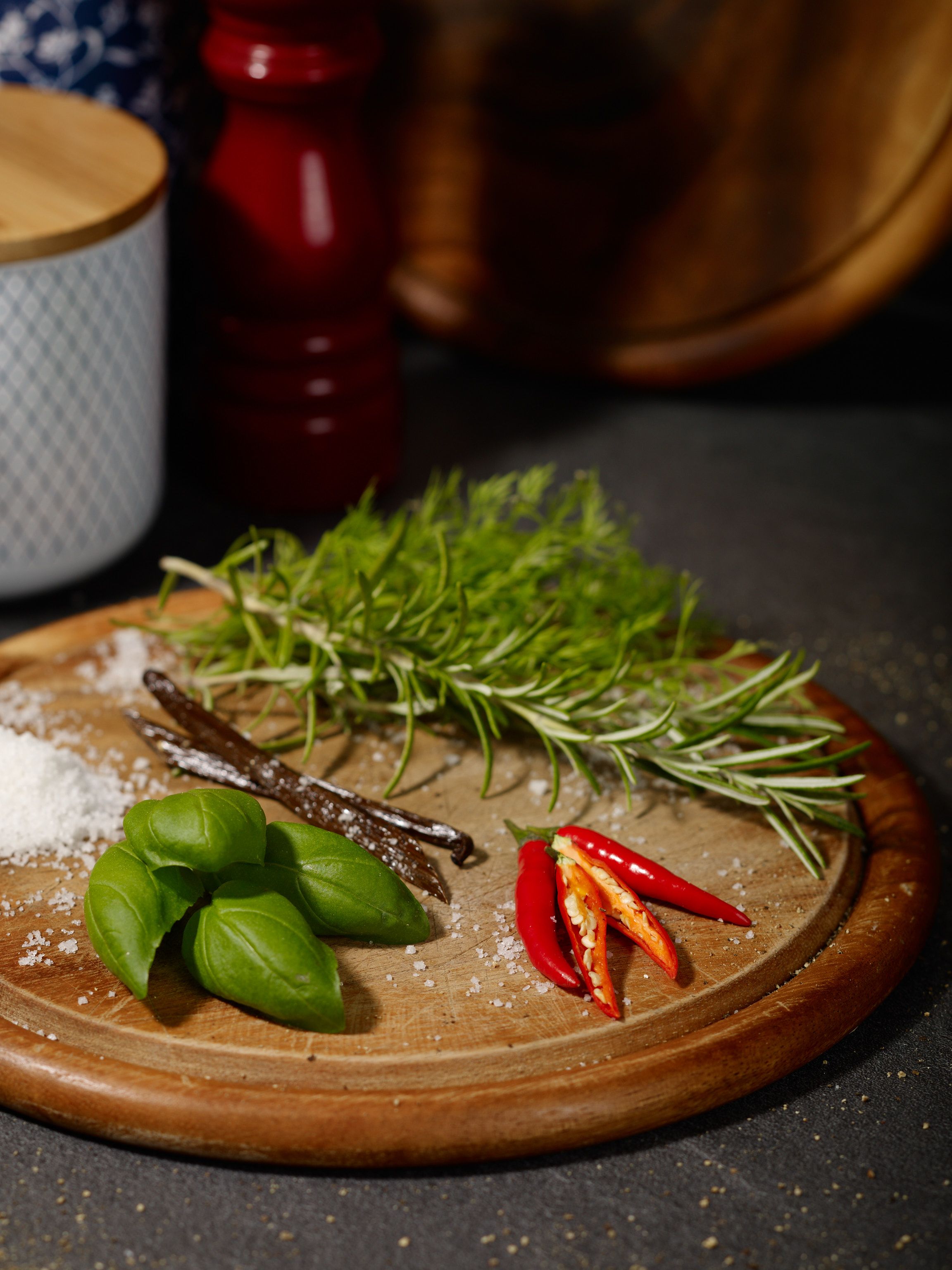 Basil, birds-eye chillies, vanilla, rosmary and salt on a chopping board
