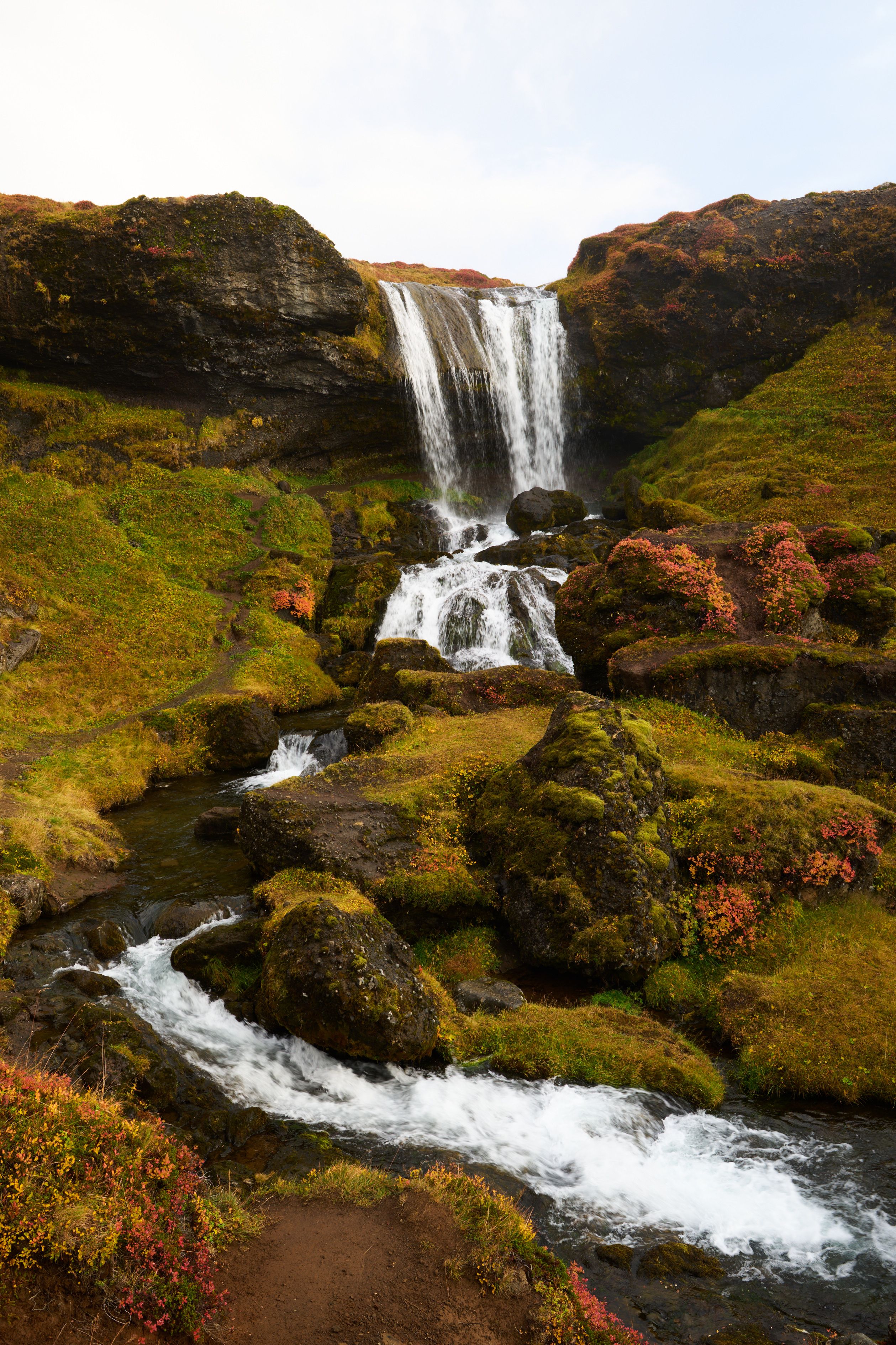 A waterfall on the Vatnaleidh pass surrounded by lush green